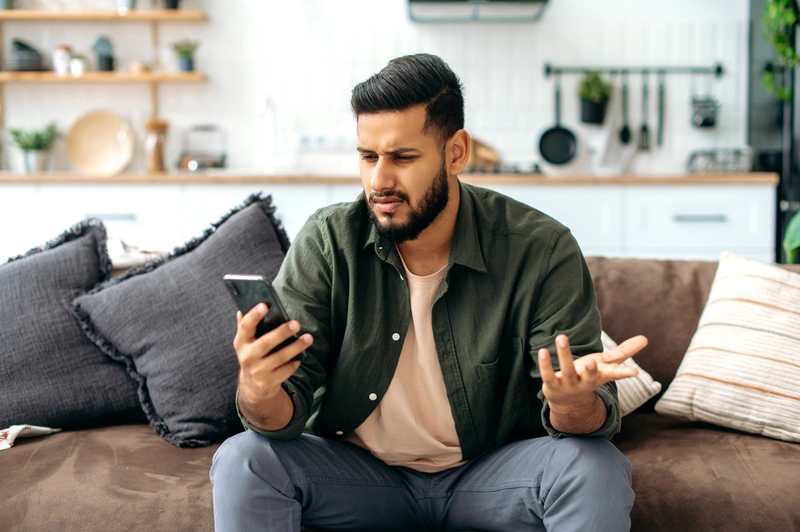 Confused man reading article about alcohol on a phone