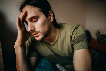 Depressed men experiencing alcohol withdrawal, sitting alone in living room