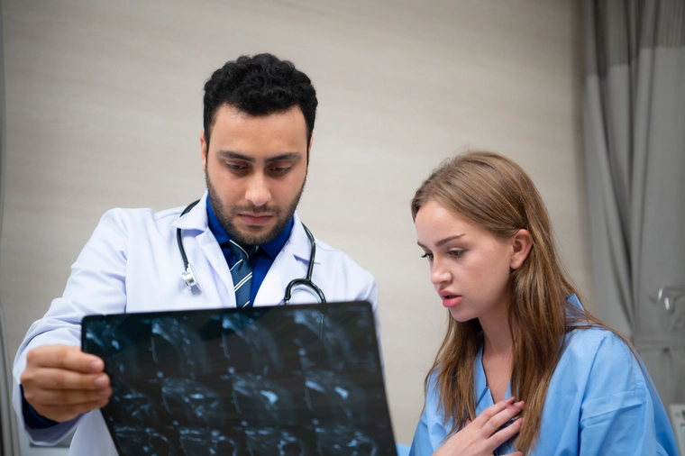 Doctor with a patient are looking at x-ray, patient is shocked.