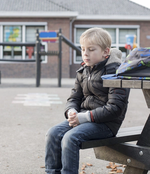 Young boy sitting by a playground, health problems 