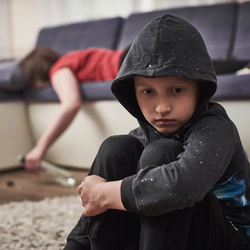 Little boy is sitting in a room with unconsious alcoholic mother