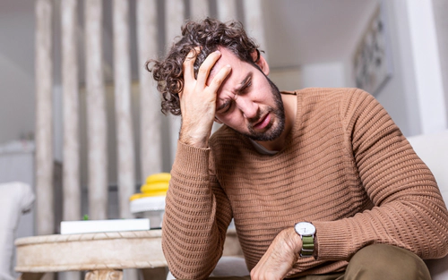 Man with his head in his hand, painful look to his face