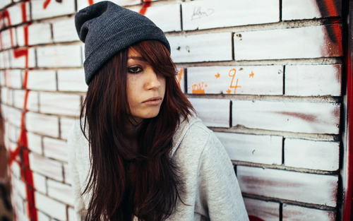 Woman leaning against a brick wall